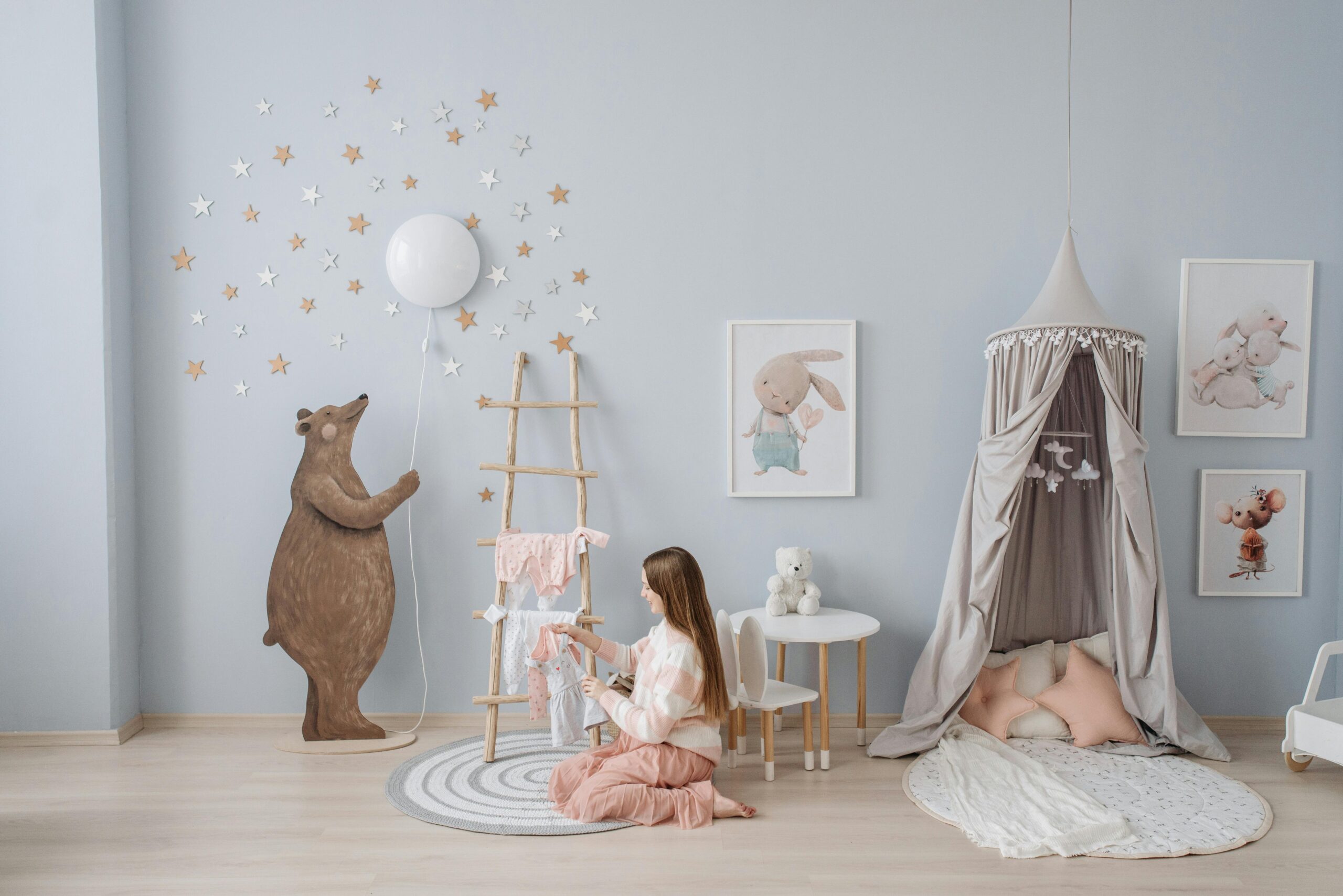Woman arranging baby clothes in a beautifully decorated nursery with playful decor.